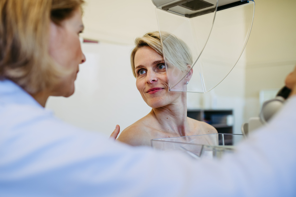 Healthcare professional adjusts the patient for accurate breast imaging. Preventive breast cancer screening.