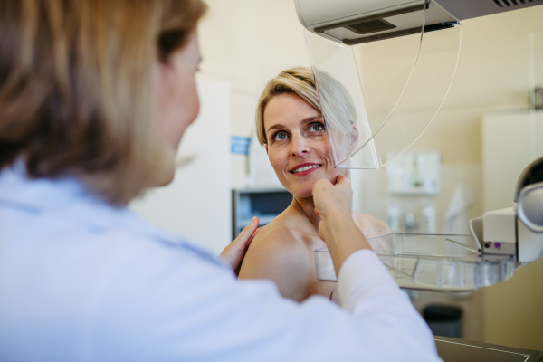 Healthcare professional adjusts the patient for accurate breast imaging. Preventive breast cancer screening.