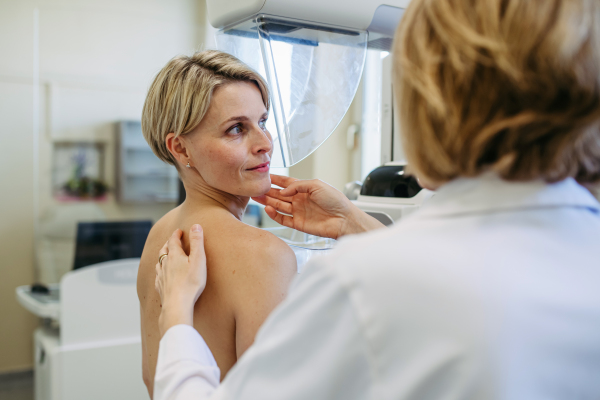 Healthcare professional adjusts the patient for accurate breast imaging. Preventive breast cancer screening.