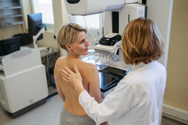 Healthcare professional adjusts the patient for accurate breast imaging. Preventive breast cancer screening.