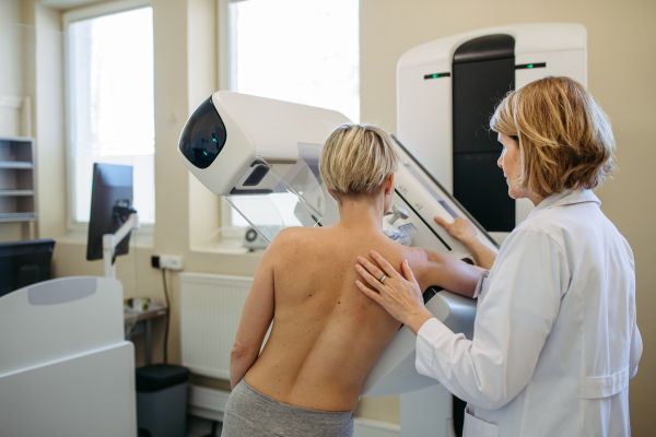 Healthcare professional adjusts the patient for proper mammogram. Preventive breast cancer screening.
