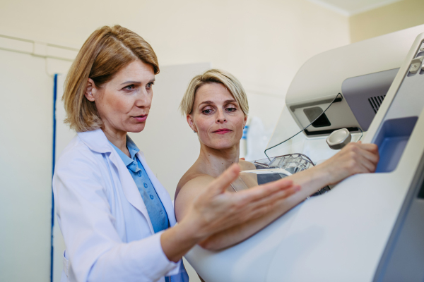 Healthcare professional adjusts the patient for accurate breast imaging. Preventive breast cancer screening.