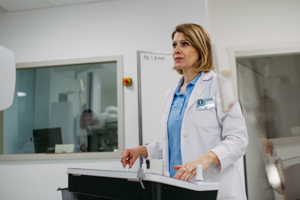 Female doctor operating dynamic X-ray scan using tilting fluoroscopy unit