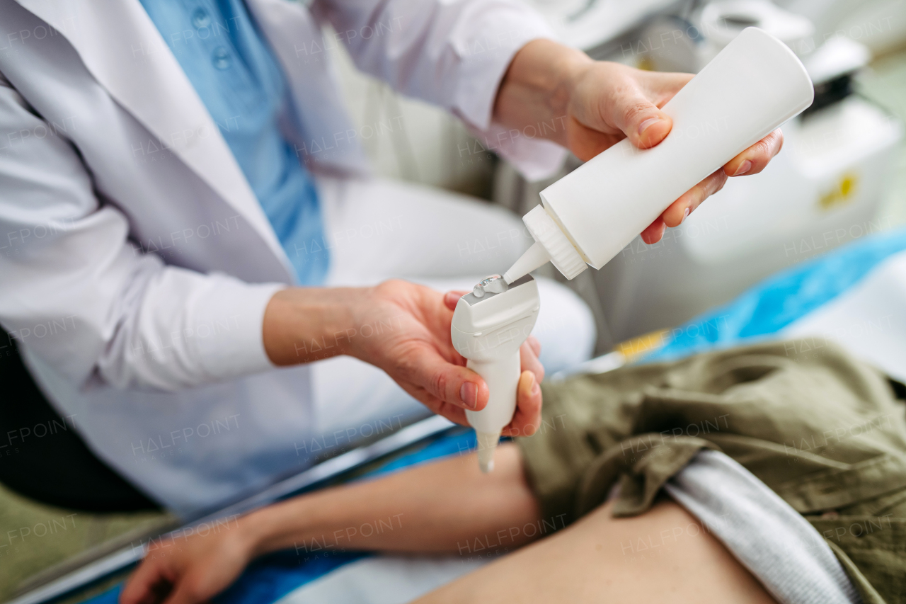 Radiologist applying gel to ultrasound probe before abdominal scan. Medical procedure.