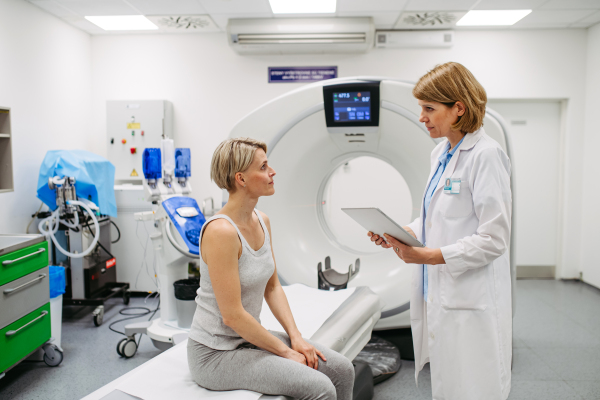 Doctor explaining results from CT scan to patient in diagnostic imaging room. Medical consultation.