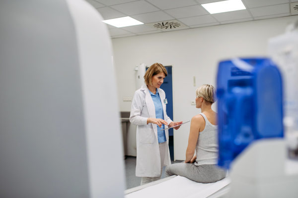 Doctor explaining results from CT scan to patient in diagnostic imaging room. Medical consultation.