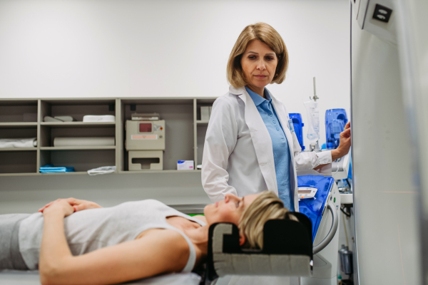 Female doctor operating CT machine and preparing patient for scan