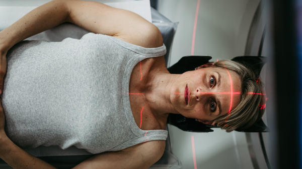 Patient positioned for head scan with laser alignment in CT scanner. Red laser lines.