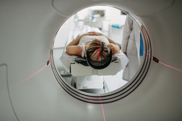 Patient positioned for head scan with laser alignment in CT scanner. Red laser lines.