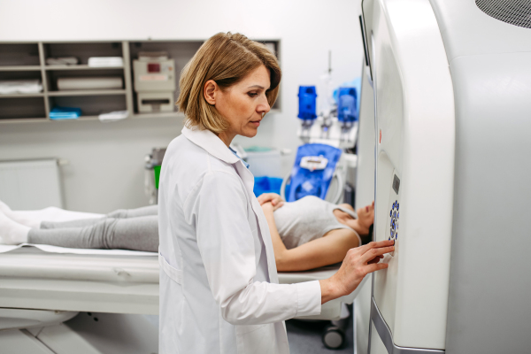 Female doctor operating CT machine and preparing patient for scan