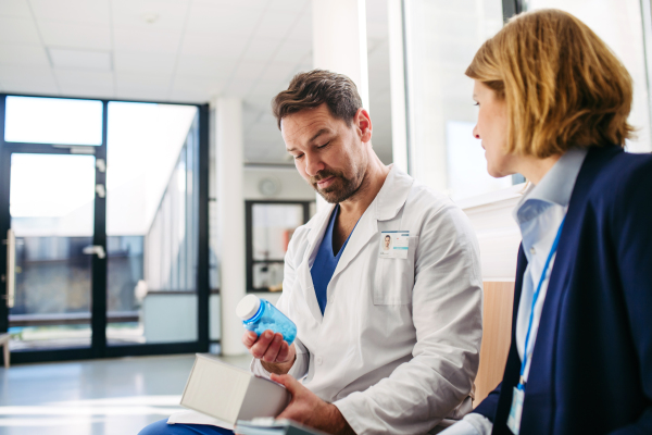 Female medical sales representative introducing pharmaceutical products to doctor. Hospital setting.