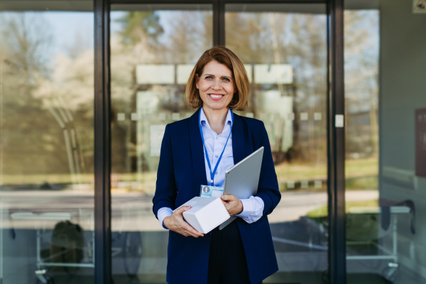 Portrait of female medical sales representative holding samples of drugs and tablet, looking at camera.