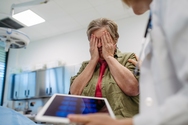 Elderly woman reacts to devastating medical test results during consultation with doctor