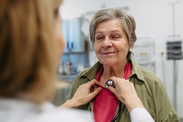 Geriatrician listening to senior patient's heartbeat. Routine health exam for elderly woman.