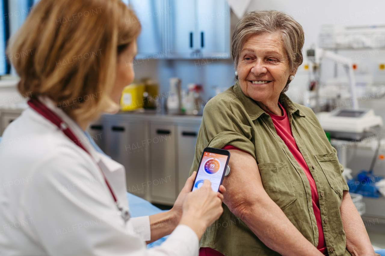 Endocrinologist teaching older patient how to connect continuous glucose monitor with mobil app. Senior health care.
