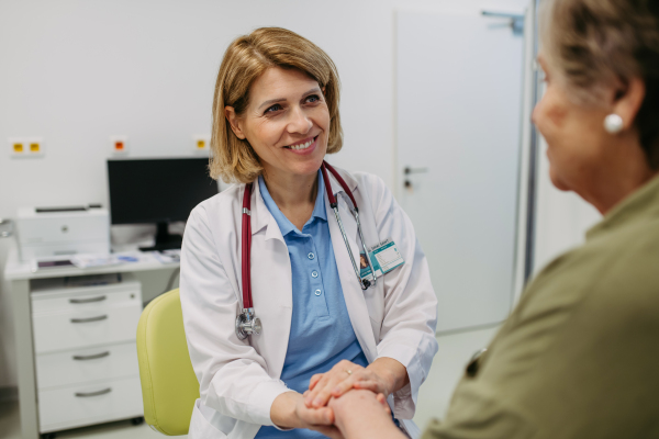 Caring doctor hands with senior patient in compassionate gesture, medical setting.