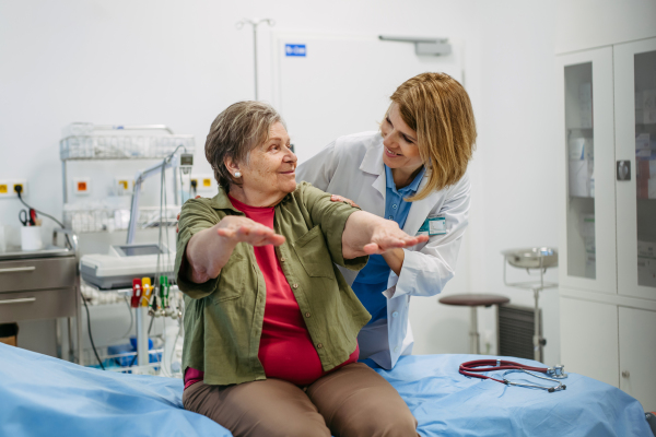 Geriatrician examining senior woman's mobility during routine check-up. Elderly care.