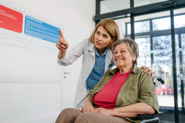 Doctor explaining something to elderly patient in wheelchair. Senior health care.
