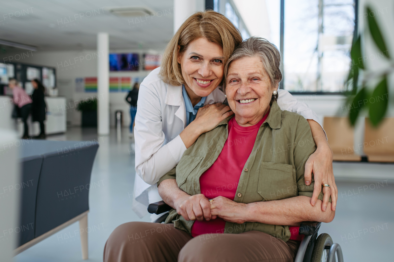 Elderly patient in wheelchair and female physician smiling at clinic. Senior health care.