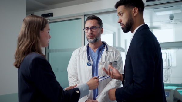A pharmaceutical sales respresentatives showing doctor new medications. Group presentation in hospital setting.