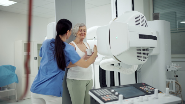 Senior woman positioned on radiographic wall stand for diagnostic imaging