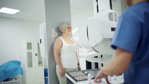 Senior woman positioned on radiographic wall stand for diagnostic imaging