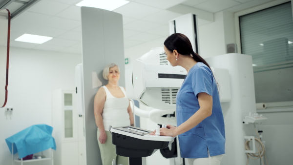 Senior woman positioned on radiographic wall stand for diagnostic imaging