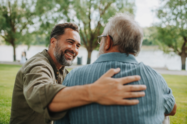 Happy dad and adult son enjoying peaceful afternoon outdoors. Fathers day concept.