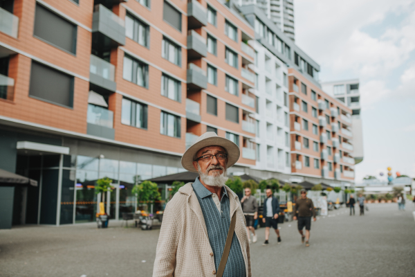 Confident senior man standing in the middle of street, visiting new city.