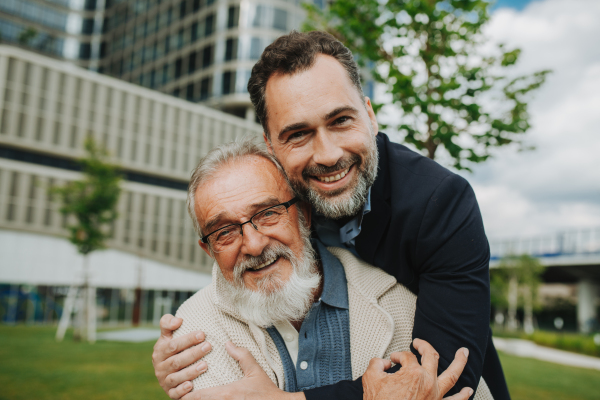 Portrait of handsome mature man and his older father hugging each other. Fathers day concept.