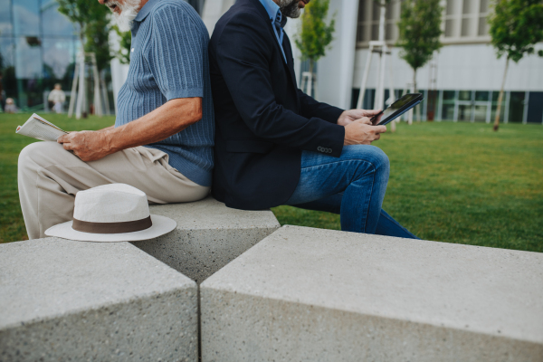Father and adult son sitting on bench in park, sharing peaceful moment. Fathers day concept.