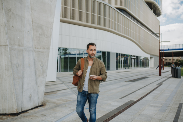 Portrait of confident middle-aged man standing outdoors by concrete wall