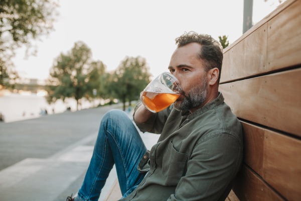 Handsome man drinking beer at outdoor pub, enjoying a peaceful evening. Open-air bar concept.