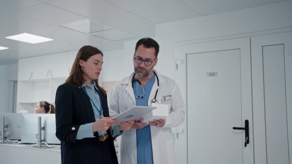Pharmaceutical sales respresentative with doctor, hospital setting.