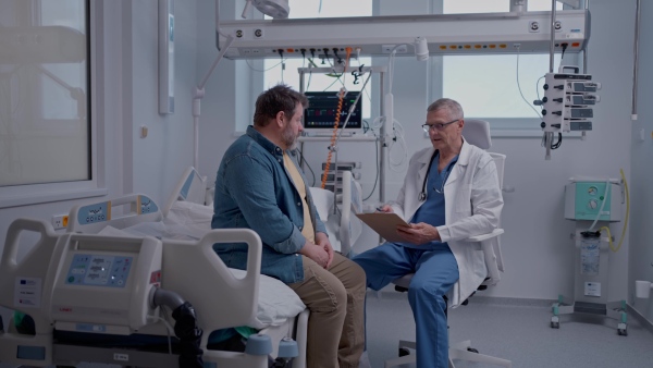 A doctor explaining the risks of leaving the hospital early as the patient prepares to sign an AMA form.