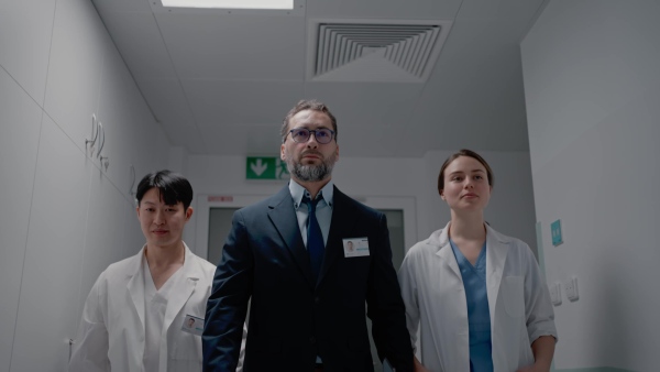 A manager with doctors walking thourgh hospital corridor.