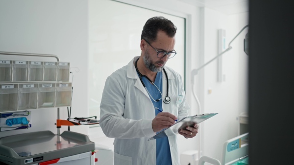A doctor in a white coat checking a hospital room and filling out a medical form on a clipboard