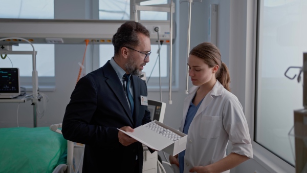 Pharmaceutical sales respresentative with doctor, hospital setting.
