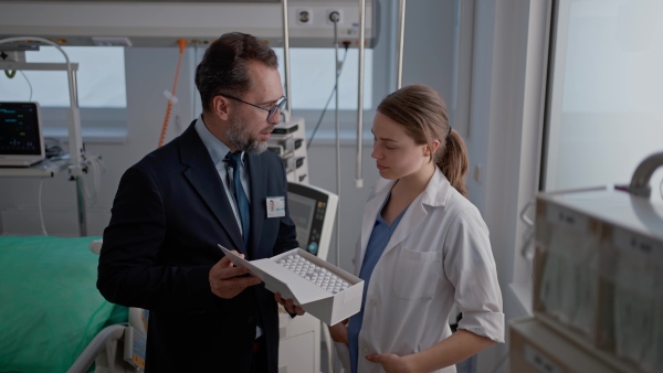 Pharmaceutical sales respresentative with doctor, hospital setting.