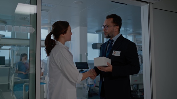 Pharmaceutical sales respresentative with doctor, hospital setting.