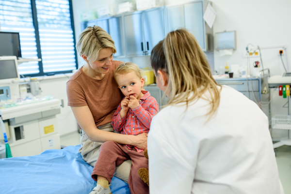 Female pediatrician talking little boy during preventive health check up.