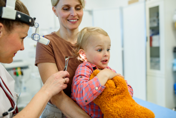Otolaryngologist examining toddler in pediatric clinic, ENT exam.