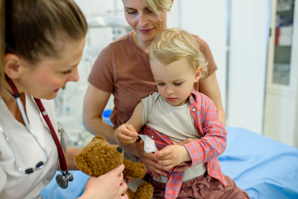 Doctor and young toddler patient treat a teddy bear during medical check up.