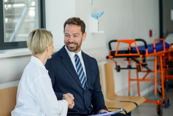 Doctor meeting pharmaceutical representative and shaking his hand in clinical setting.