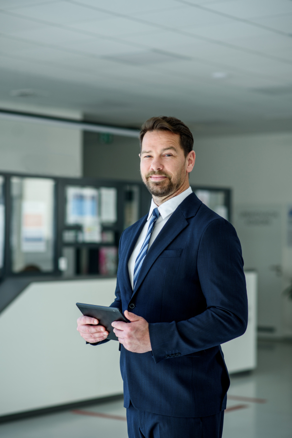 Business professional standing with tablet in hand, ready for presentation, sales representative.