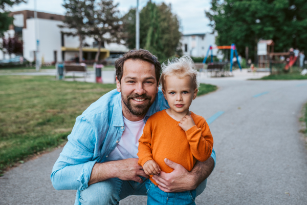 Father playing with toddler son outdoors in city park
