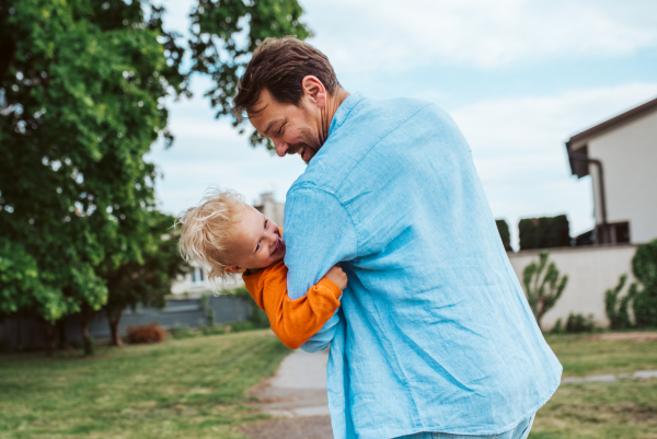 Father playing with toddler son, holding him upside down. Fun time.