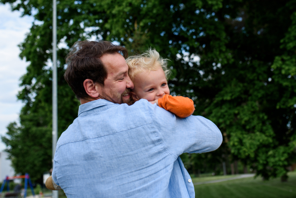 Portrait of dad hugging little son, enjoying time together. Fathers day concept.