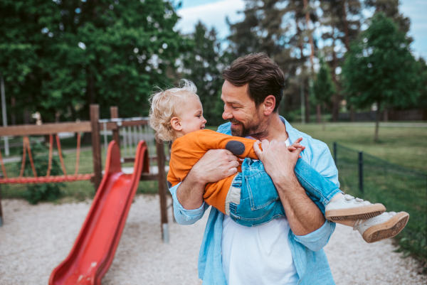 Father playing with toddler son outdoors in city park