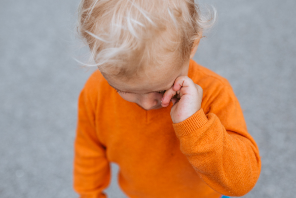 Portrait of a crying toddler boy in a park